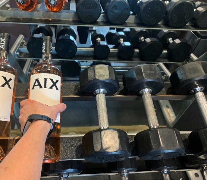 Woman taking AIX Rose magnum wine bottle from dumbbell rack