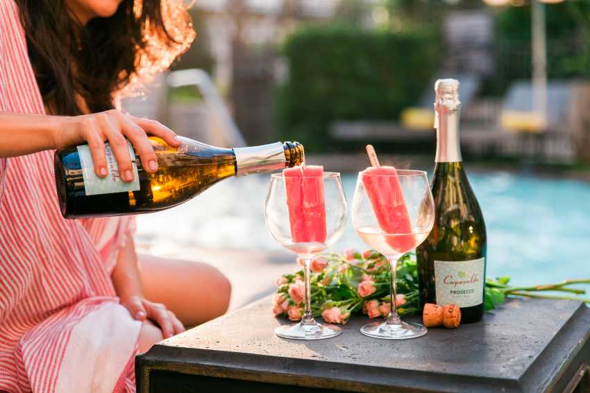 Pouring Prosecco into wineglasses with popsicles