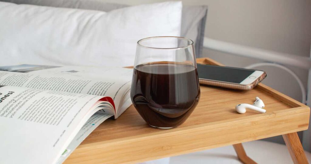 Wine in bedroom with airpods and magazine