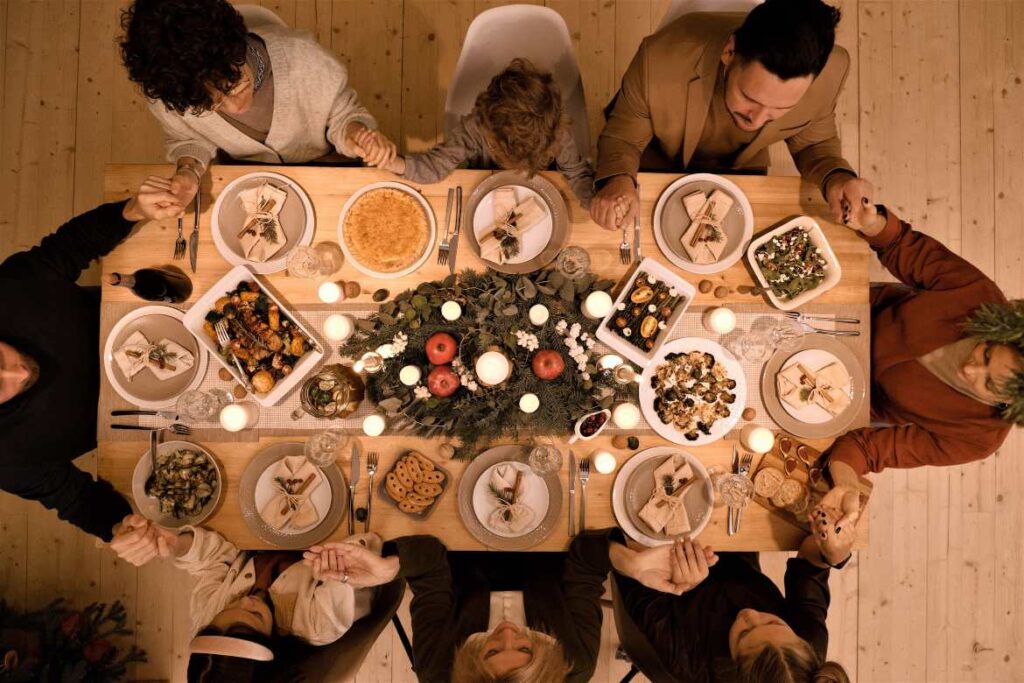 holiday feast, group around table holding hands