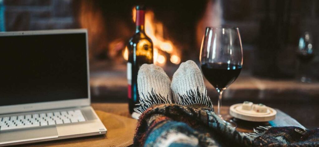 Wine, socks, quilt, computer in front of fire