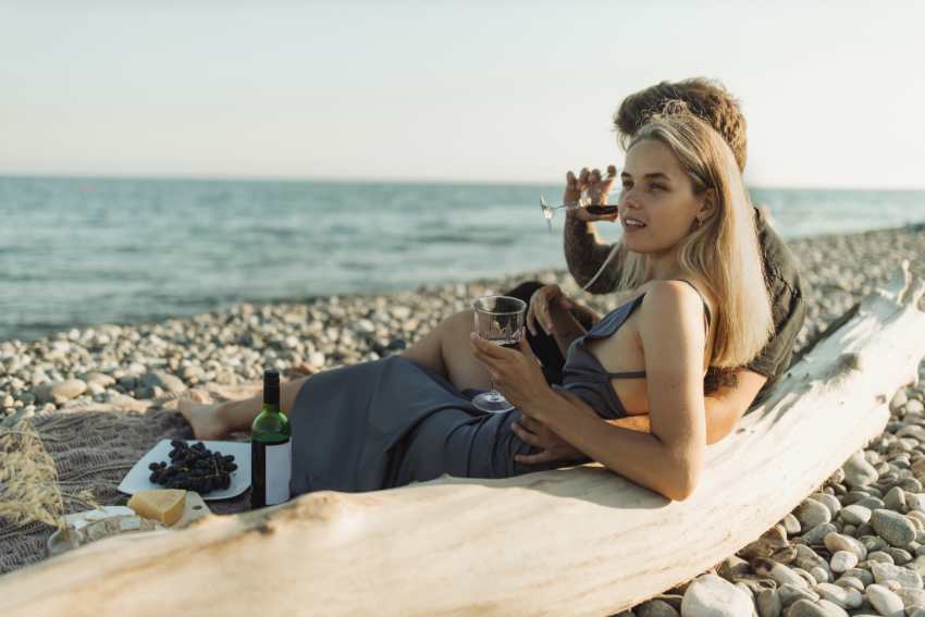 couple at a beach drinking wine with picnic