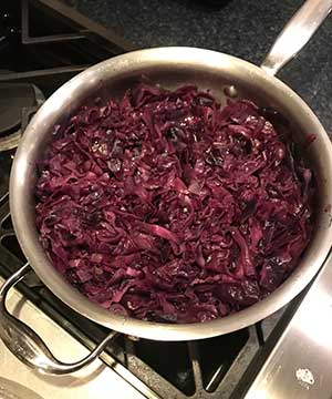 Red cabbage cooking in a stainless steel pan on a stove top