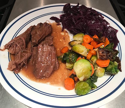 Dinner plate of pot roast, roasted brussels sprouts and carrots, and braised red cabbage