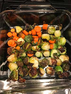 Roasted brussels sprouts and carrots in a glass dish