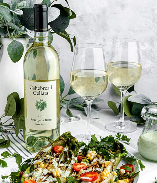 Cakebread Sauvignon Blanc white wine bottle and two glasses with a salad