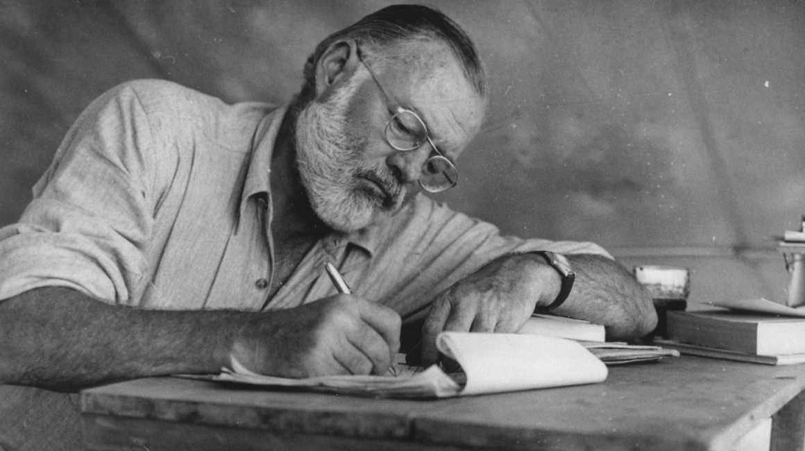 Ernest_Hemingway_Writing_at_Campsite_in_Kenya_-_NARA_-_192655 (1)