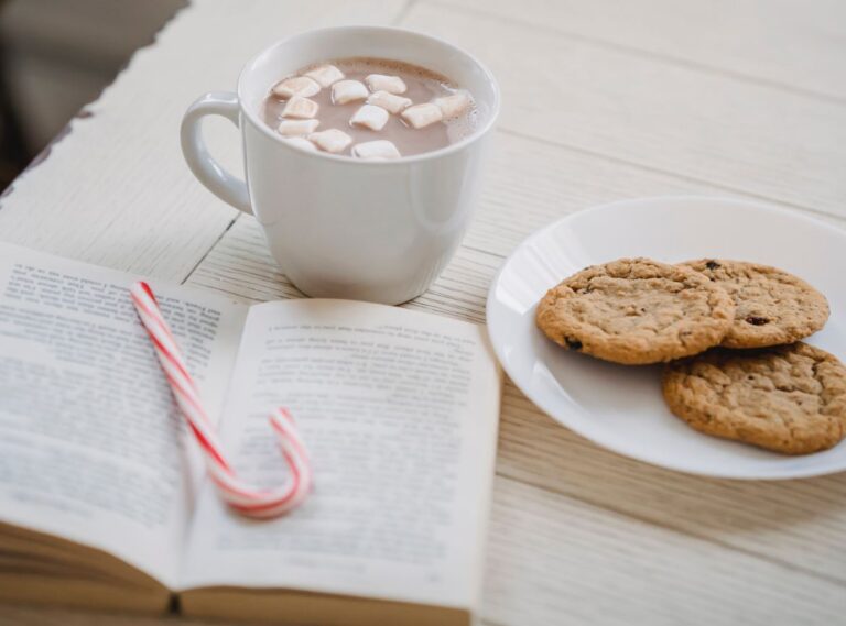 Drinking hot cocoa with cookies, candy cane, and book