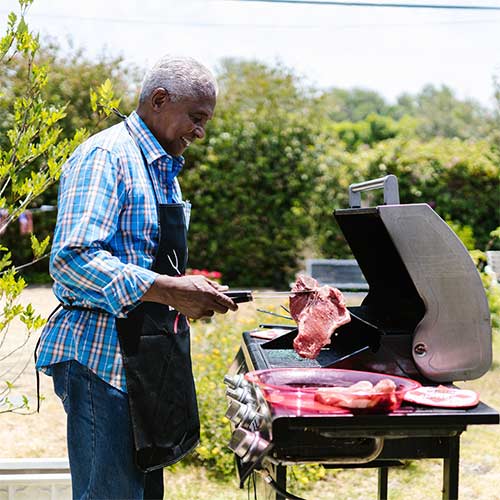 A man cooking meat outside on a bbq grill for father's day