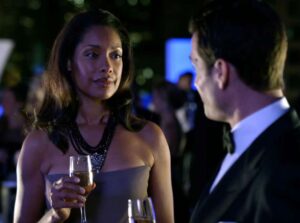 Scene from the TV show suits showing Jessica Pearson holding a glass of Champagne while talking to Harvey Specter at a cocktail party