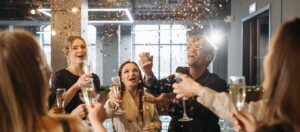 Group of young people in an apartment celebrating with Champagne and looking up at festive confetti